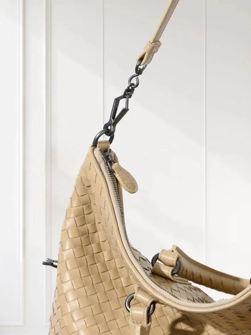 Beige woven leather tote bag with detachable strap and silver hardware against white background