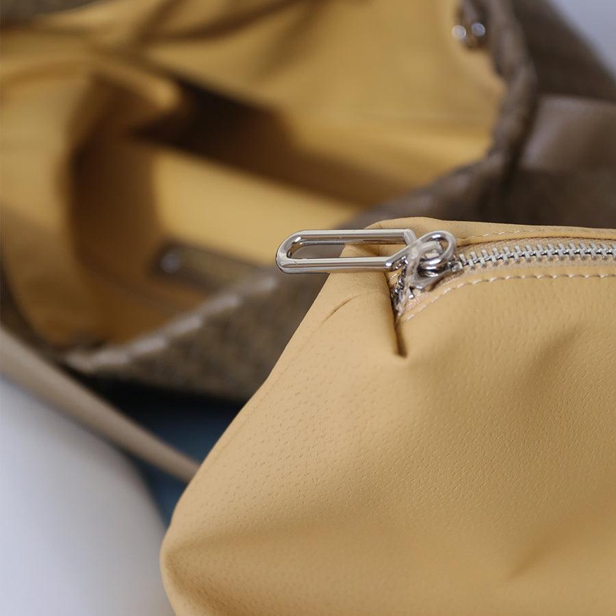 Close-up of beige woven leather tote bag interior with silver zipper pouch