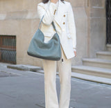 Woman in white suit carrying large woven lambskin leather tote bag on city street