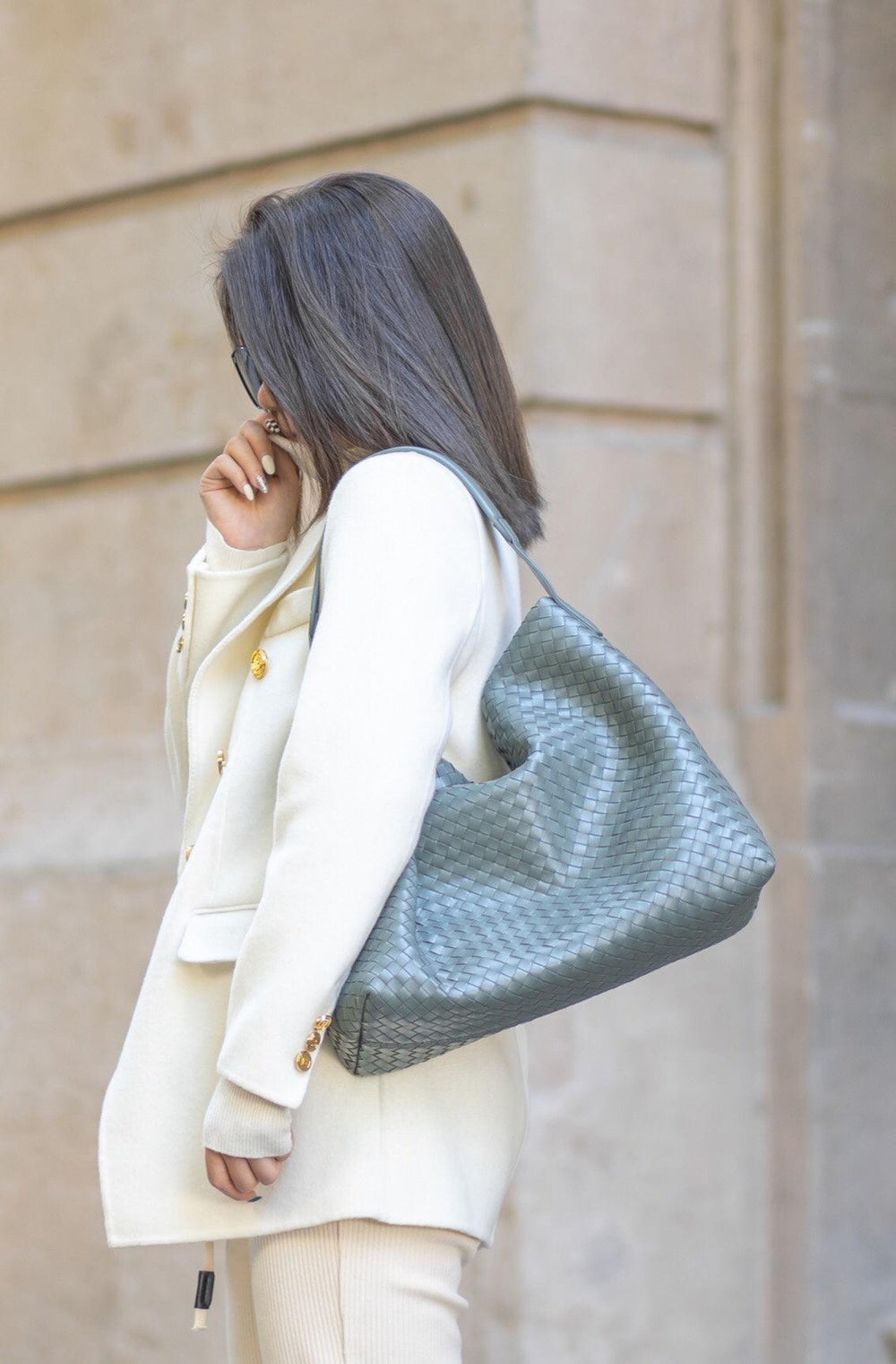 Woman carrying large woven lambskin leather tote bag on shoulder, street style outfit