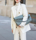 Woman in white suit holding large woven lambskin leather tote bag with shoulder strap