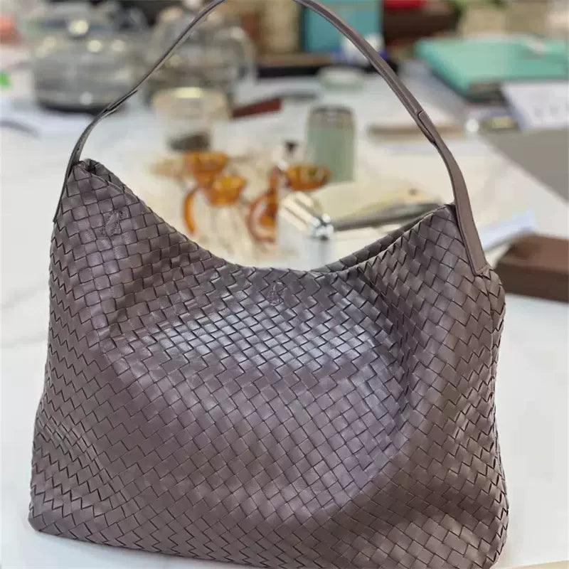 Large brown woven lambskin leather tote bag with single shoulder strap on a table.