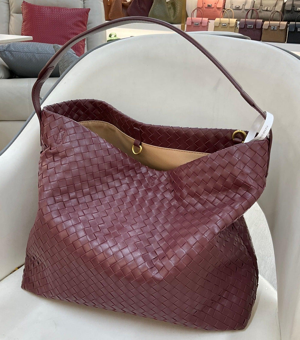 Large burgundy woven lambskin leather tote bag with shoulder strap, displayed on a chair