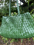 Green woven leather hobo bag with trapezoidal shape and double handles, outdoors