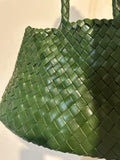 Green woven leather hobo bag with trapezoidal shape and braided handles, close-up view