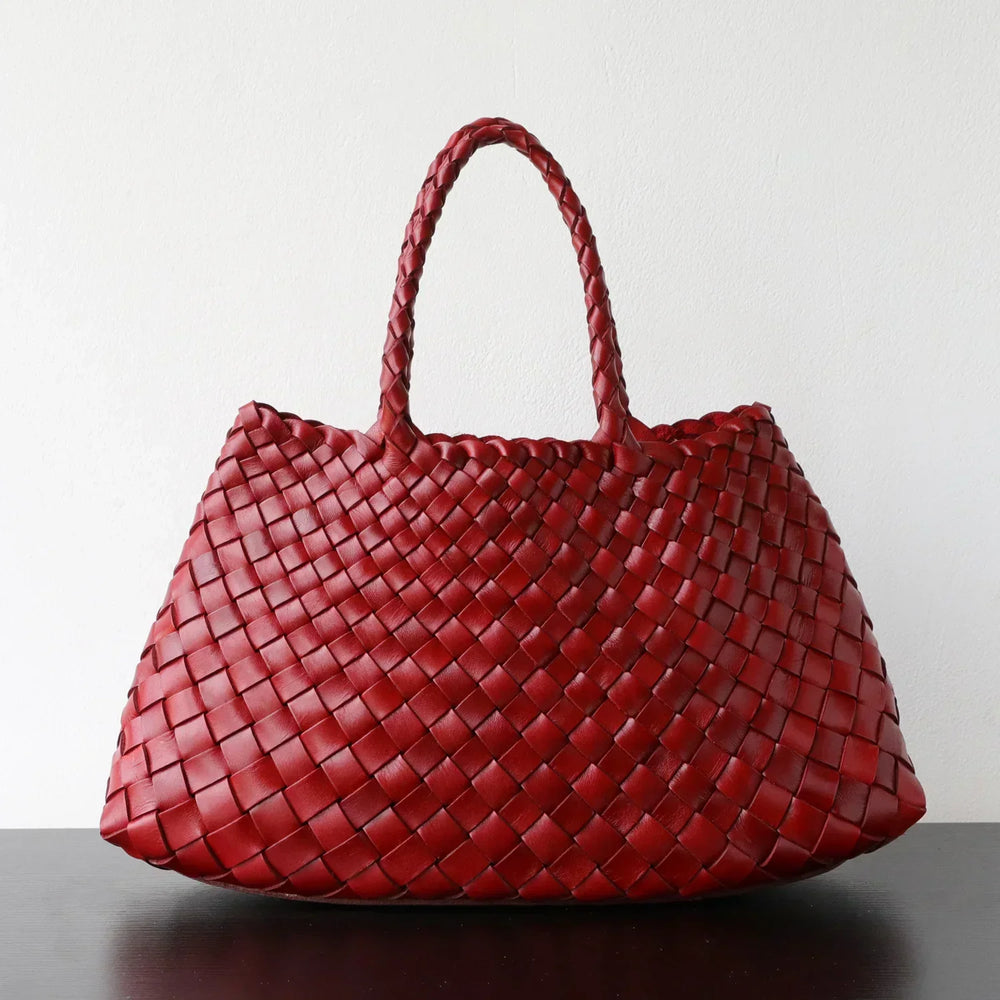 Red woven leather hobo shoulder bag with trapezoidal shape and long handle on a plain background