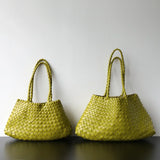 Two olive green woven leather hobo shoulder bags with long handles on a black surface