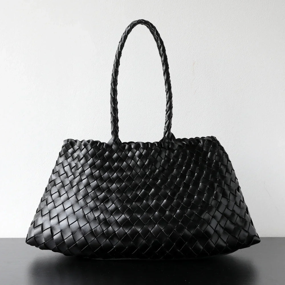 Black woven leather hobo shoulder bag with long handle, trapezoidal shape on plain background