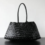 Black woven leather hobo shoulder bag with long handle, trapezoidal shape on plain background