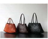 Three woven leather hobo shoulder bags in brown, dark brown, and black on a table.