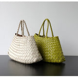 Woman holding trapezoidal woven leather hobo bag with braided handles, neutral pearl white