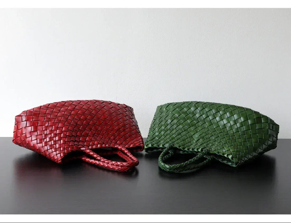 Red and green woven leather hobo shoulder bags with long handles on a black surface