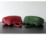 Red and green woven leather hobo shoulder bags with long handles on a black surface