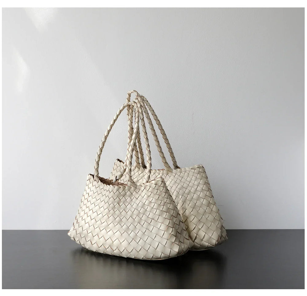 Woman holding trapezoidal woven leather hobo bag with braided handles, neutral pearl white