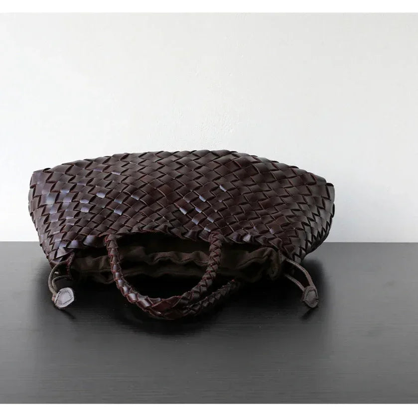 Dark brown woven leather hobo shoulder bag with long handles on black table