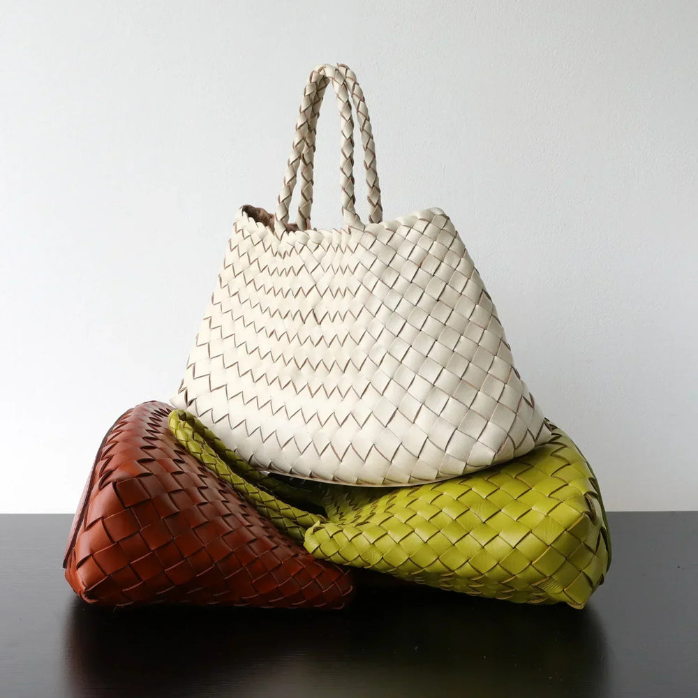 Woman holding trapezoidal woven leather hobo bag with braided handles, neutral pearl white