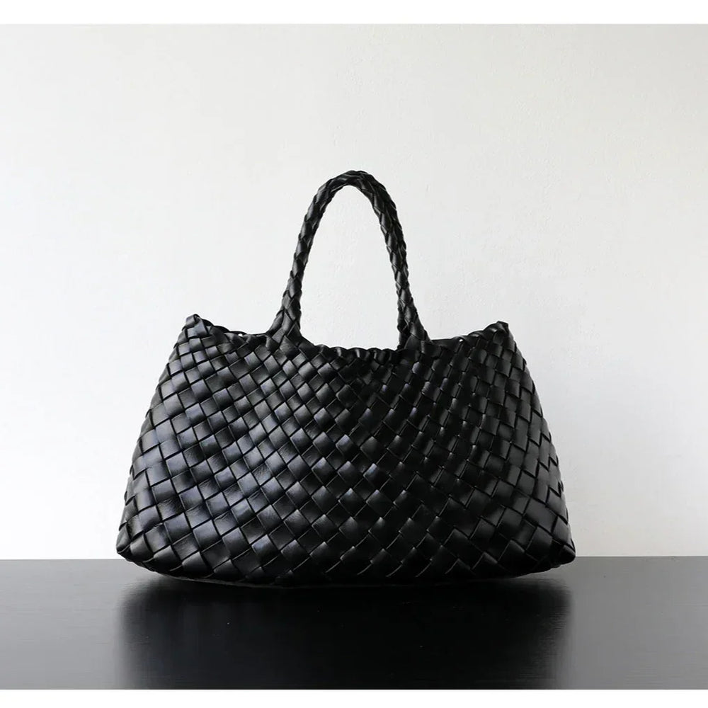 Woman holding black woven leather hobo bag with dual handles, stylish and trapezoidal shape black