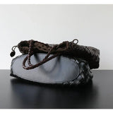 Woman holding black woven leather hobo bag with dual handles, stylish and trapezoidal shape black