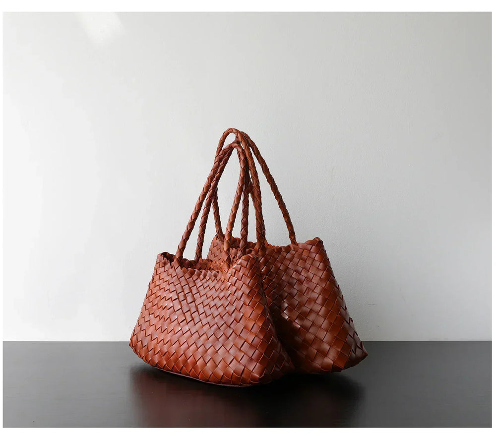 Brown woven leather hobo shoulder bags with long handles on a dark table against white wall