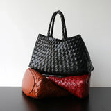 Trio of woven leather hobo shoulder bags in black, brown, and red on a dark table