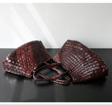 Handcrafted brown woven leather hobo bags with long handles on a dark surface