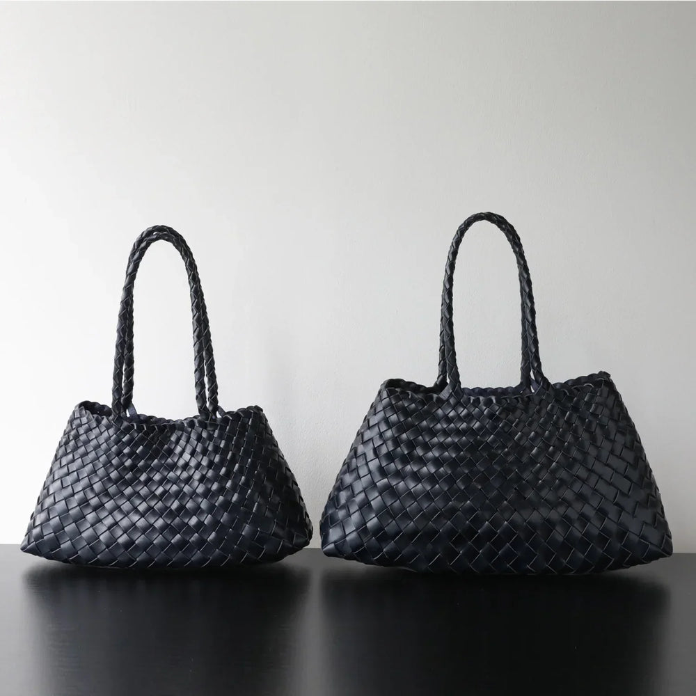 Black woven leather hobo shoulder bags with long handles on black table, minimal background