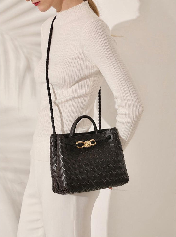Woman wearing black lambskin woven leather shoulder bag with gold metal buckle