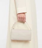 Mini beige lambskin leather Boston bag with top handle, held by person in cream coat