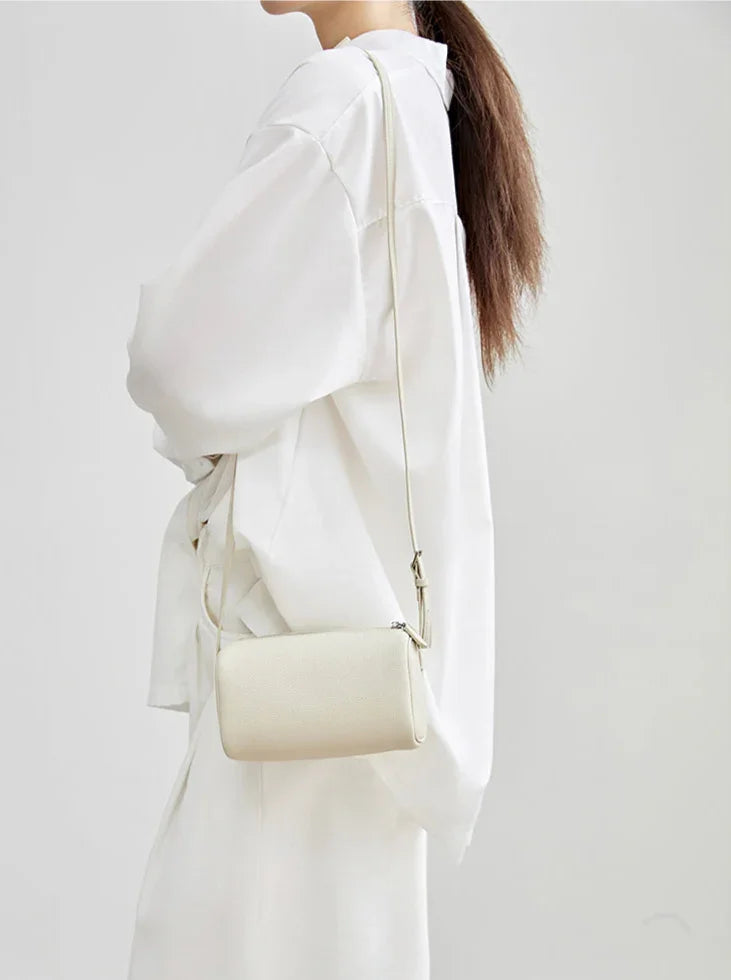 Minimalist cream lambskin leather box bag with shoulder strap, worn over white outfit