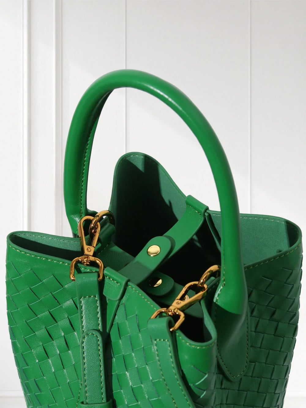 Green handwoven lambskin leather bucket bag with gold hardware and top handle, close up