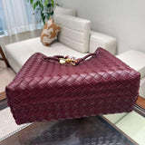 Burgundy woven lambskin leather shoulder bag with metal buckle, displayed on glass table