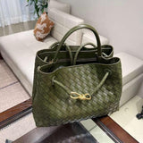 Olive green woven lambskin leather shoulder bag with gold metal buckle on a glass table