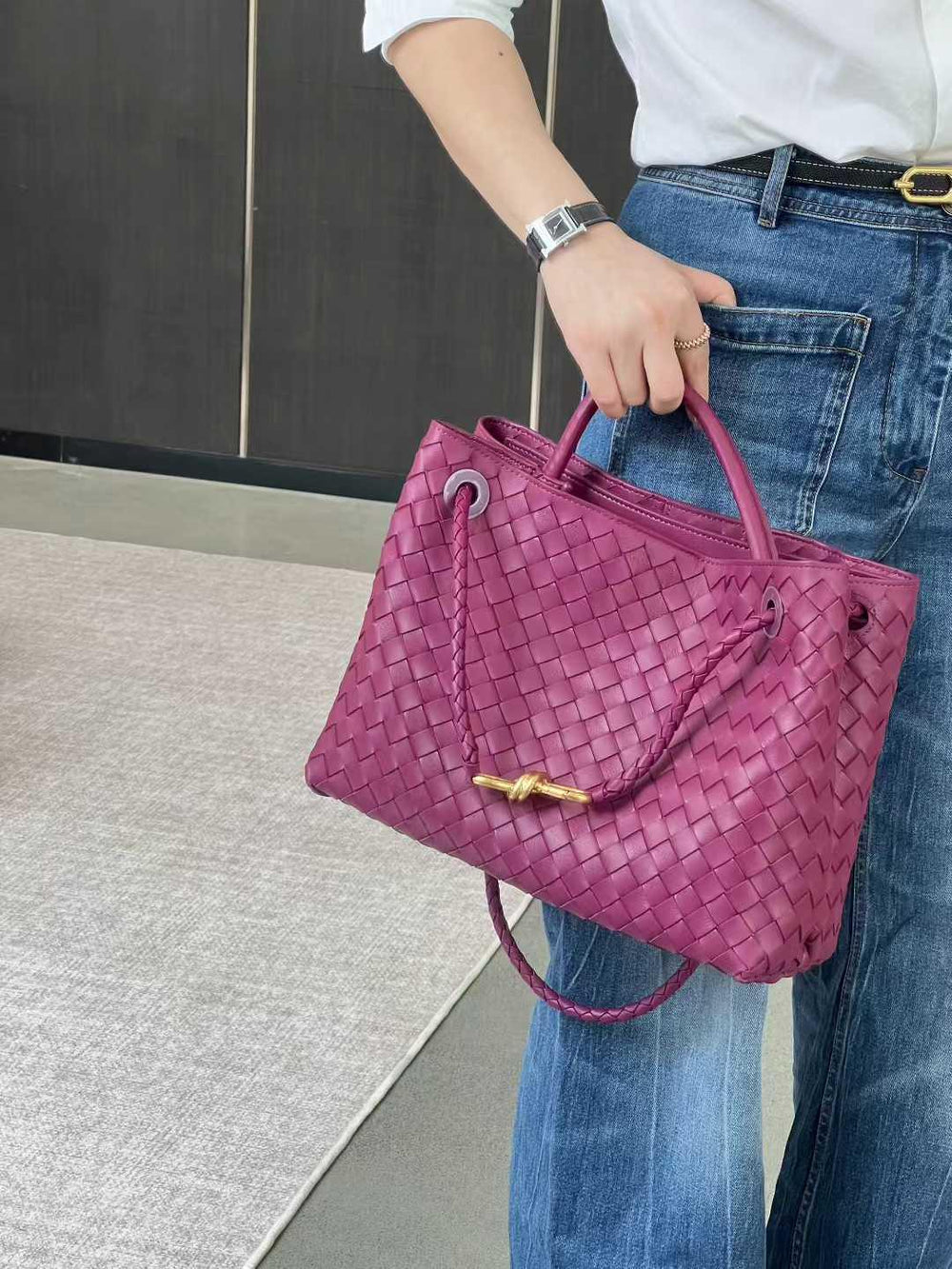 Purple lambskin woven leather shoulder bag with metal buckle, held by woman in jeans