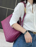 Woman carrying a purple woven lambskin leather shoulder bag with gold buckle detail