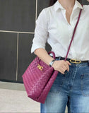 Woman holding a purple lambskin woven leather shoulder bag with gold buckle, casual outfit