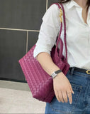 Woman carrying a purple lambskin woven leather shoulder bag with gold knotted buckle detail