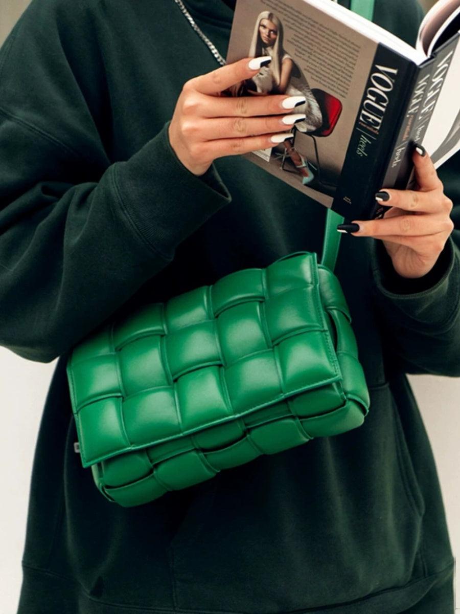 Woman holding a magazine with a green lambskin leather quilted shoulder bag