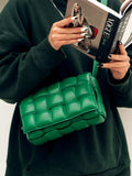 Woman holding a magazine with a green lambskin leather quilted shoulder bag