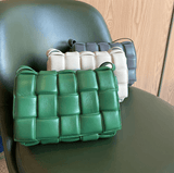 Green, ivory, and grey lambskin leather quilted shoulder bags with woven design on a chair