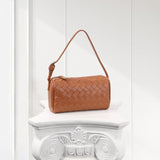 Tan woven lambskin leather mini handbag with short strap, displayed on white pedestal