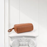Tan woven lambskin leather Boston bag with wrist strap on ornate white pedestal
