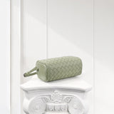 Sage green woven lambskin leather mini Boston bag with shoulder strap on a white pedestal