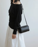 Woman wearing a black woven lambskin leather mini crossbody bag with adjustable strap