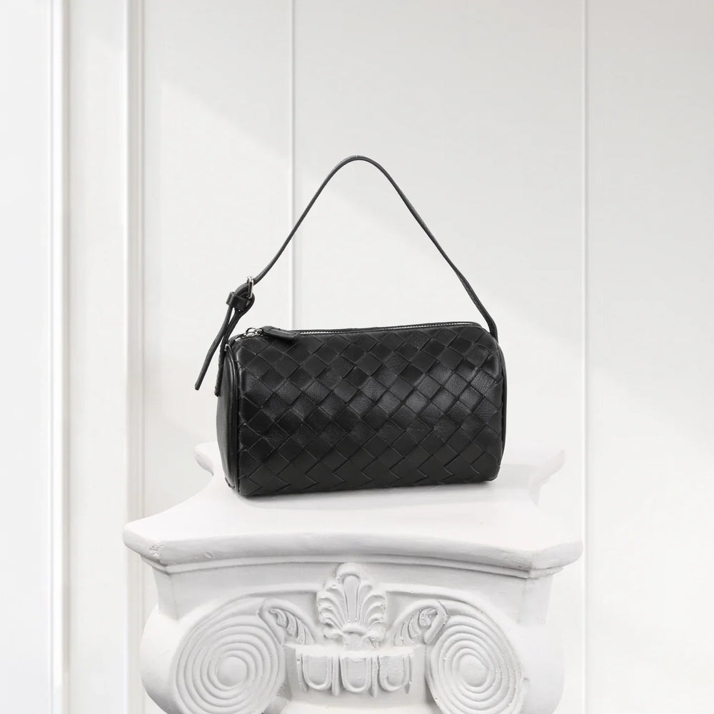 Black woven lambskin leather mini Boston bag with top handle on white pedestal