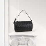 Black woven lambskin leather mini Boston bag with top handle on white pedestal