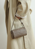 Mini woven lambskin leather crossbody bag with adjustable strap, styled on a neutral trench coat.