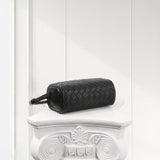 Black lambskin leather woven mini Boston bag with boxy shape on white ornate pedestal