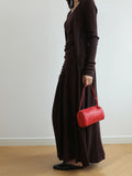 Woman in brown knit outfit holding a red lambskin woven leather mini Boston bag