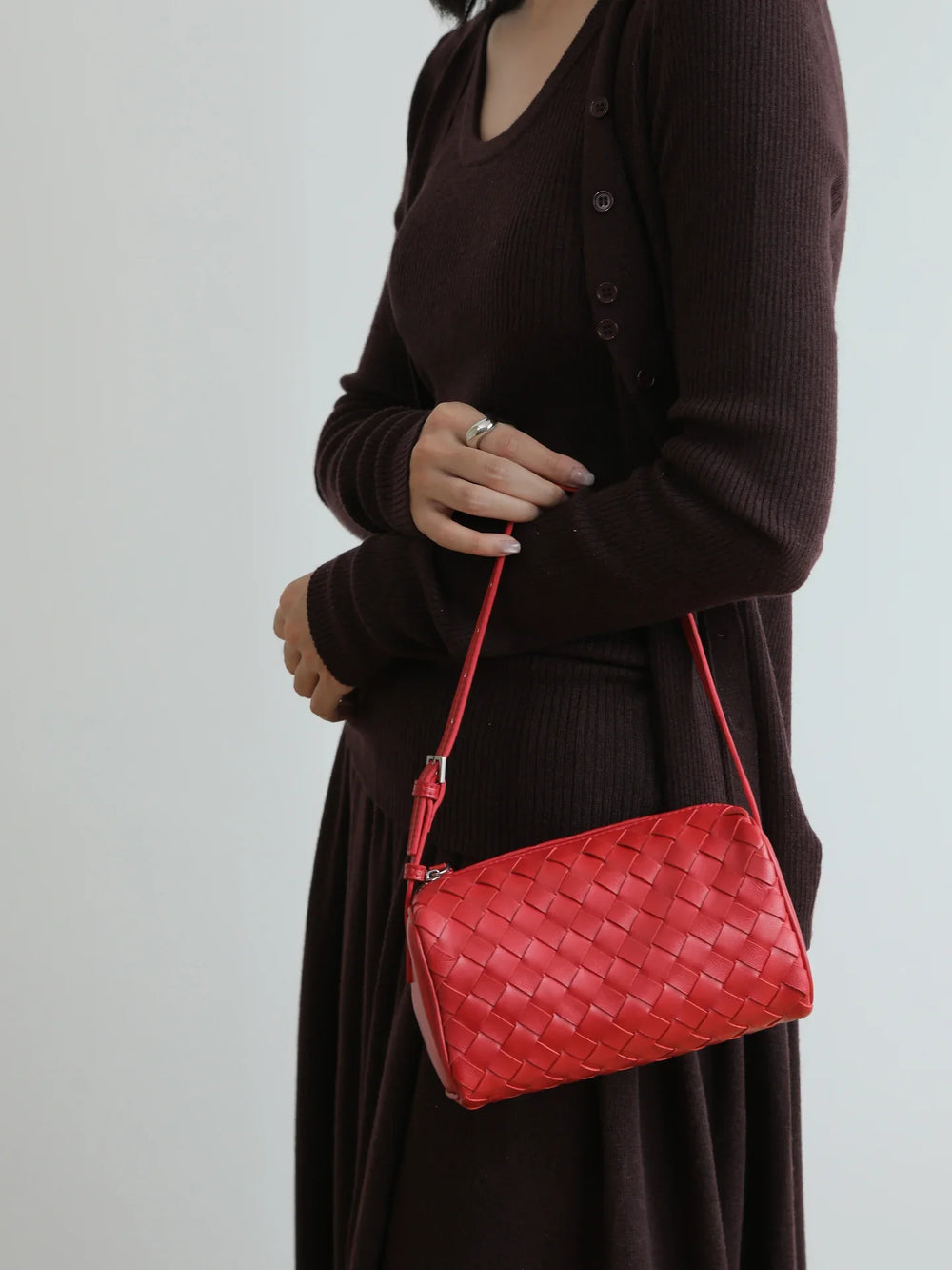 Woman holding a red lambskin leather woven mini Boston bag with shoulder strap