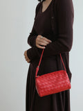 Woman holding a red lambskin leather woven mini Boston bag with shoulder strap